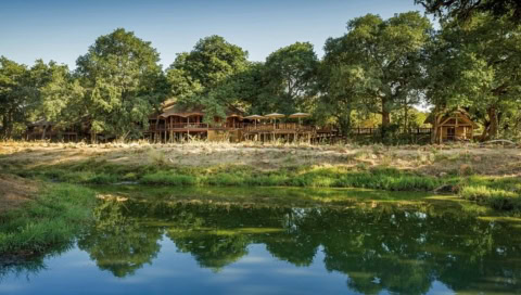 Wasserloch mit Lodge im Hintergrund