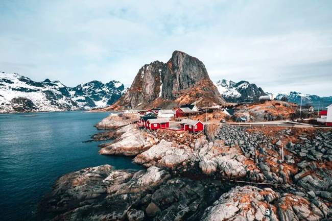 Norwegische Felslandschaft an der Meeresküste mit wenigen roten Holzhäusern.