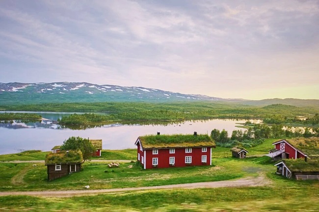Schwedische Landschaft mit See, Bauernhof und Bergen im Hintergrund