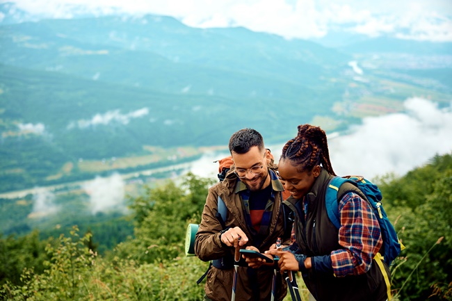 Paar beim Wandern in den Bergen nutzen Smartphone-App als Guide