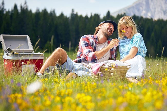 Ein Paar genießt ein Picknick auf einer Blumenwiese.