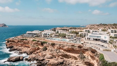 Luftaufnahme des 7Pines Resort Ibiza auf einer Klippe über dem Meer mit weitem Blick auf die Küste