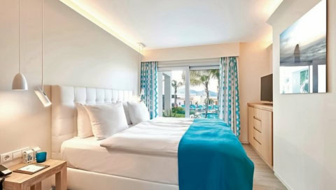 Helles Schlafzimmer mit Meerblick, Doppelbett und türkisfarbenen Akzenten im 7Pines Resort Ibiza