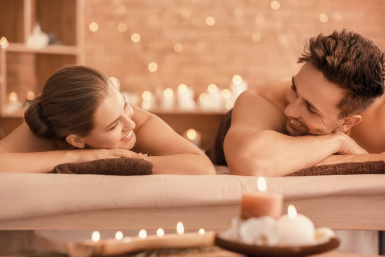Paar liegt nebeneinander in einem Wellnessbereich und lächelt sich an