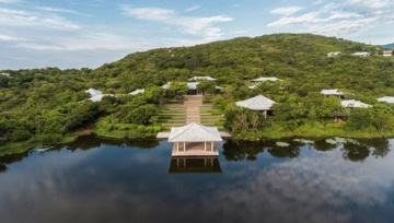 Weitläufige Hotelanlage mit Pavillon am Wasser und Villen im grünen Hügel