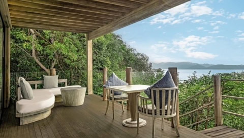 Überdachte Holzterrasse mit Sitzgruppe und Meerblick.
