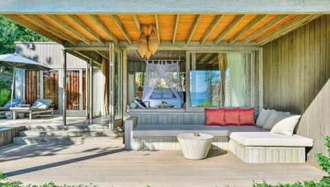 Terrasse mit überdachtem Sitzbereich und Blick ins Schlafzimmer mit Himmelbett.