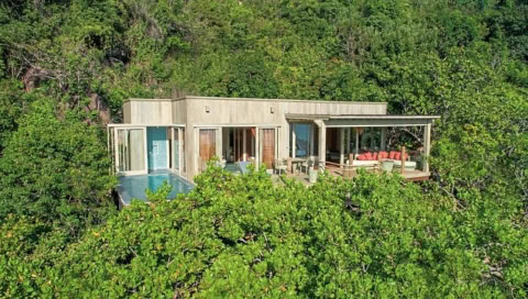 Offene Villa mit Pool, umgeben von dichter grüner Vegetation.