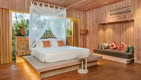 Schlafzimmer mit Holzverkleidung, Himmelbett und gemütlicher Sitzecke.