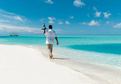 Kellner bringt eine Flasche Wein am Strand