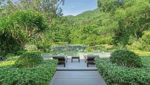 Holzterrasse mit Liegen und Ausblick auf einen Pool im Grünen