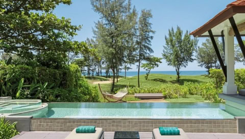 Terrasse mit Infinity-Pool, Liegen und Hängematte, dahinter Bäume und Meer