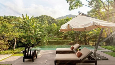 Privater Pool mit zwei Sonnenliegen und Sonnenschirm in tropischer Umgebung