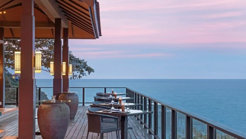 Terrasse mit Tischen und Stühlen, Meerblick und Sonnenuntergangsstimmung