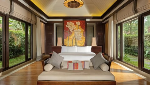 Modern eingerichtetes Zimmer mit großem Bett, Kunstwerk und Fensterfronten