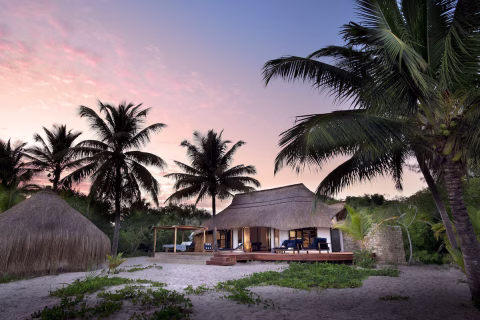 Offener Lounge-Bereich mit Sofas, Holzdeck und Blick ins tropische Grün