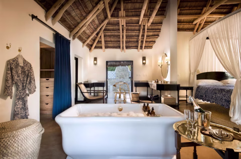 Offenes Badezimmer mit freistehender Badewanne, Naturmaterialien und Strohdach