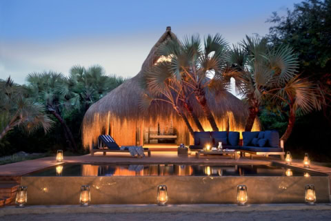 Privater Pool einer Strandvilla mit Liegestühlen und Palmen im Hintergrund