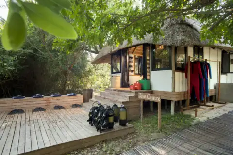 Tauchbasis der Lodge mit Ausrüstung und Neoprenanzügen unter schattigen Bäumen