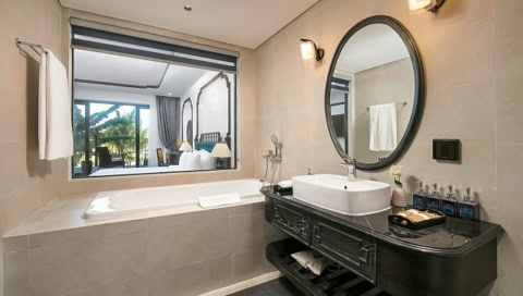 Modernes Badezimmer mit Badewanne, Waschtisch und Blick ins Schlafzimmer