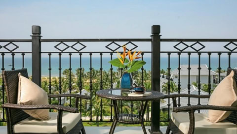 Balkon mit Sitzgruppe und Meerblick über Palmenlandschaft