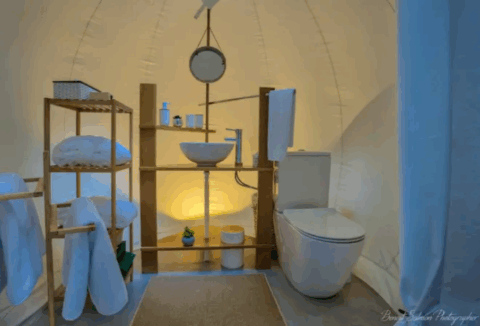 Modernes, helles Badezimmer mit Waschbecken, Regalen und Toilette in einer Bubble-Suite