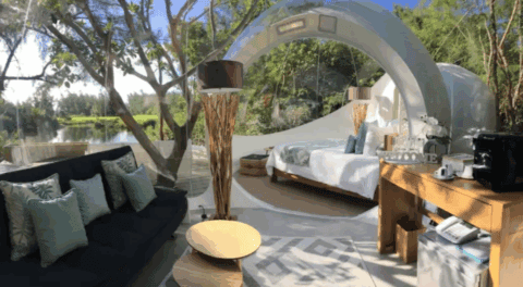 Wohn- und Schlafbereich in einer transparenten Bubble-Suite mit Blick auf den See und umgebende Bäume