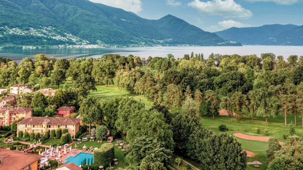 Hotelanlage des Giardino Ascona am Lago Maggiore mit Pool, Parklandschaft und umliegenden Bergen