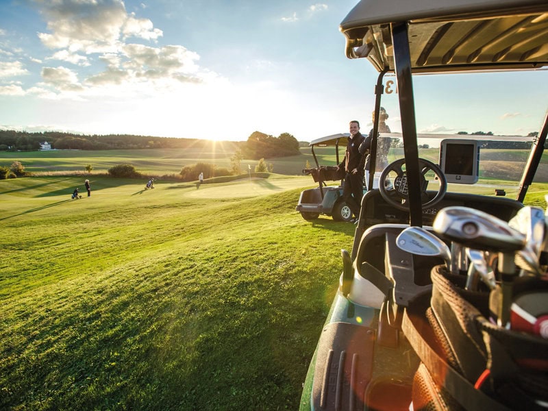 Golfanlage nahe dem Grand Hotel Heiligendamm bei tief stehender Sonne mit Golfcart, Golfausrüstung, gepflegten Fairways und weitem Grün