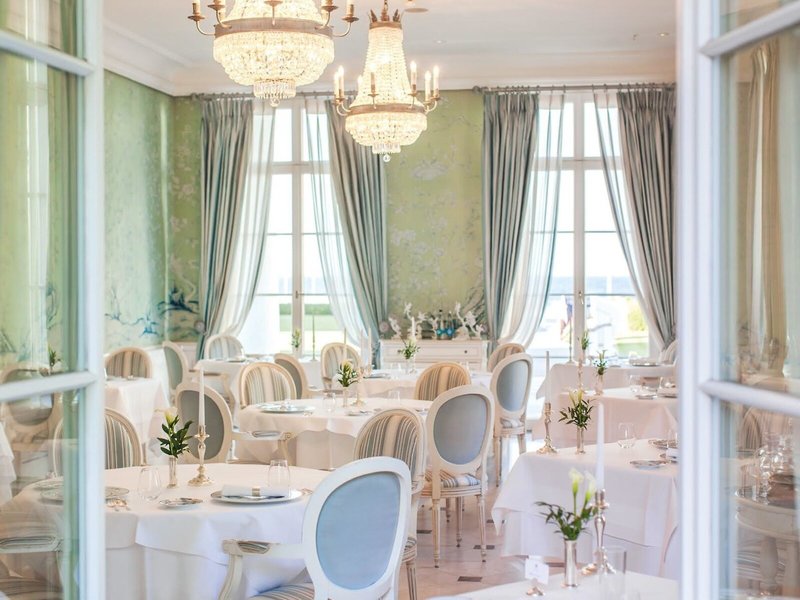 Stilvolles Restaurant im Grand Hotel Heiligendamm mit weißen Tischdecken, Kronleuchtern, hohen Fenstern und hellem Blick Richtung Ostsee
