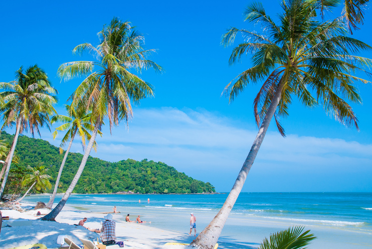 Paradiesischer Strand auf Phu Quoc mit Palmen, weißem Sand und türkisblauem Meer unter strahlend blauem Himmel.