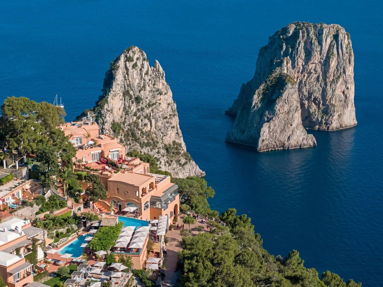 Luftaufnahme des Hotel Punta Tragara auf Capri mit Pool, Terrassen und Blick auf die Faraglioni-Felsen