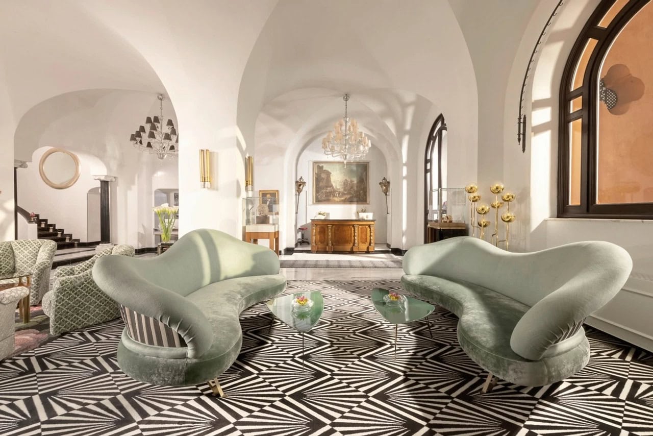 Eleganter Wohnbereich im Hotel Punta Tragara auf Capri mit geschwungenen Sofas, hohen Gewölben und großem Fenster