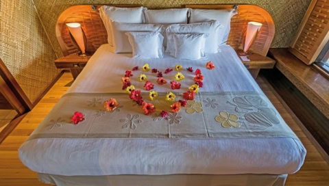 Hotelbett mit einem Herz aus Blüten