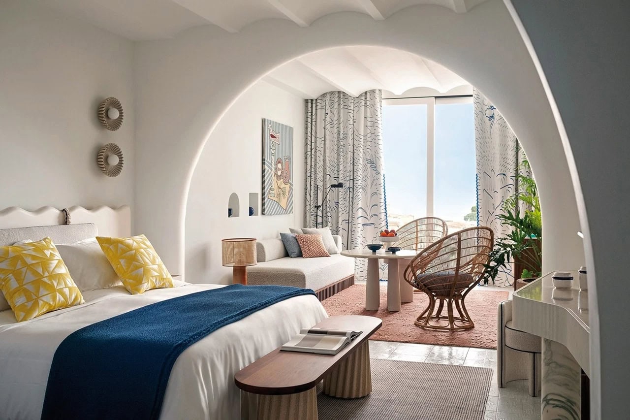 Modernes Doppelzimmer im Jumeirah Capri Palace mit Rundbogen, Sitzecke, Rattanstühlen und blauen Farbakzenten