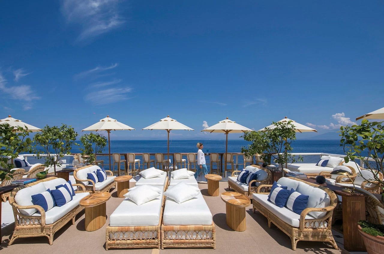 Sonnige Outdoor-Lounge im Jumeirah Capri Palace mit weißen Polstermöbeln, Sonnenschirmen und weitem Meerblick