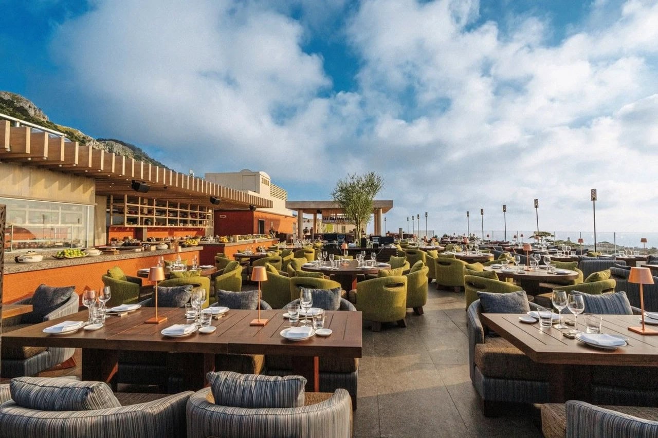 Großzügiges Outdoor-Restaurant im Jumeirah Capri Palace mit gedeckten Tischen, Loungesesseln und Blick Richtung Meer