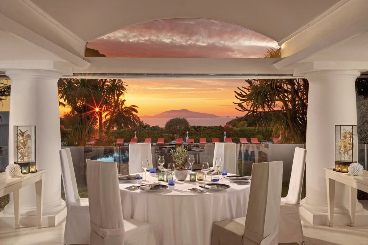 Eleganter Restaurantbereich im Jumeirah Capri Palace mit gedecktem Tisch, Sonnenuntergang und Blick auf das Meer