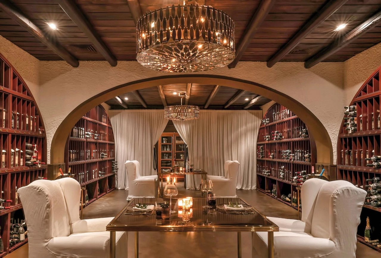 Stimmungsvolles Weinrestaurant im Jumeirah Capri Palace mit Weinregalen, weißen Sesseln, Kerzenlicht und Kronleuchter