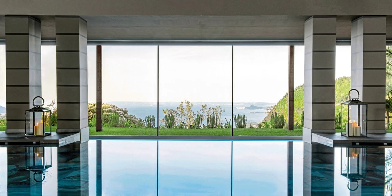 Indoorpool im Lefay Resort & Spa Lago di Garda mit großen Fenstern und Blick auf Garten und Gardasee