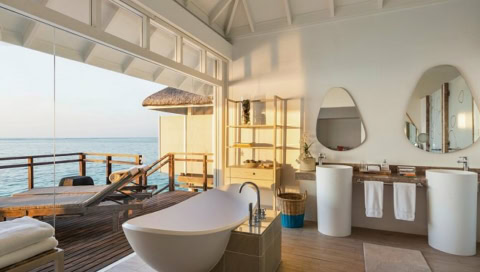 Badezimmer in einer Suite, die Glasfront lässt sich öffnen, sodass man von der Badewanne direkt auf das Meer schauen kann