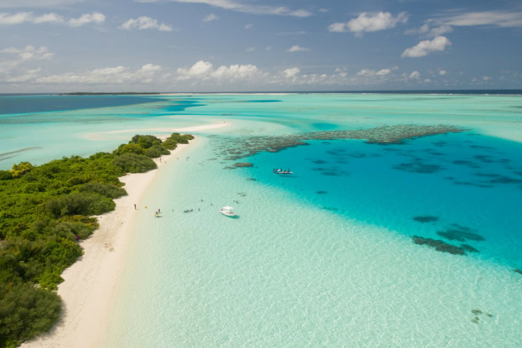 Türkisfarbene Lagune mit Sandbank und kristallklarem Wasser auf den Malediven, Luftaufnahme einer Inselkulisse.