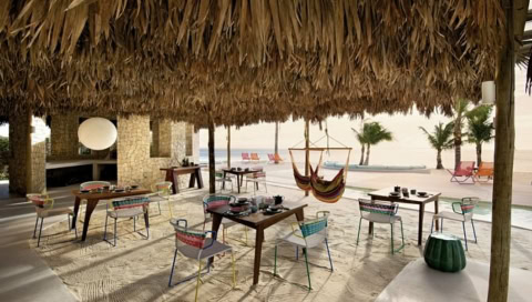 Hängematten und Tische mit Stühlen am Strand