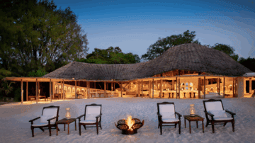 Außenbereich der Lodge direkt am Strand mit Feuerstelle und Liegestühlen im Sand