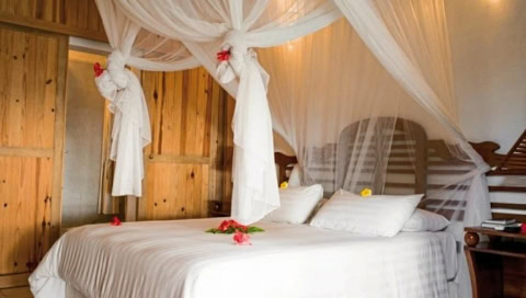 Doppelbett mit weißen Laken und Vorhängen.