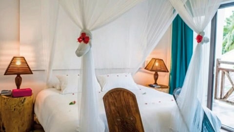 Doppelbett mit weißen Laken und Vorhängen.