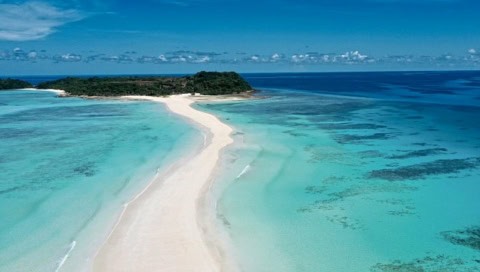 Eine lange Sandbank führ zu einer tropischen Insel.