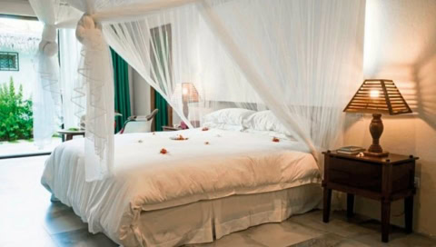 Doppelbett mit weißen Laken und Vorhängen.