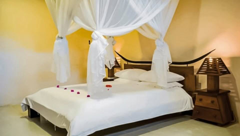 Doppelbett mit weißen Laken und Vorhängen.