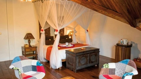 Doppelbett mit weißen Laken und Vorhängen.